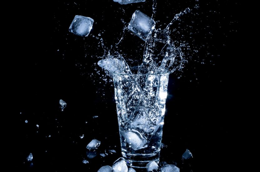 Glass of water and ice cubes splashing upwards